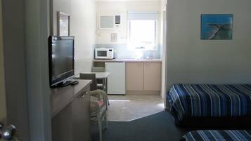 Habitación de hotel compacta con kitchenette, televisor, cama y ventana con vistas.