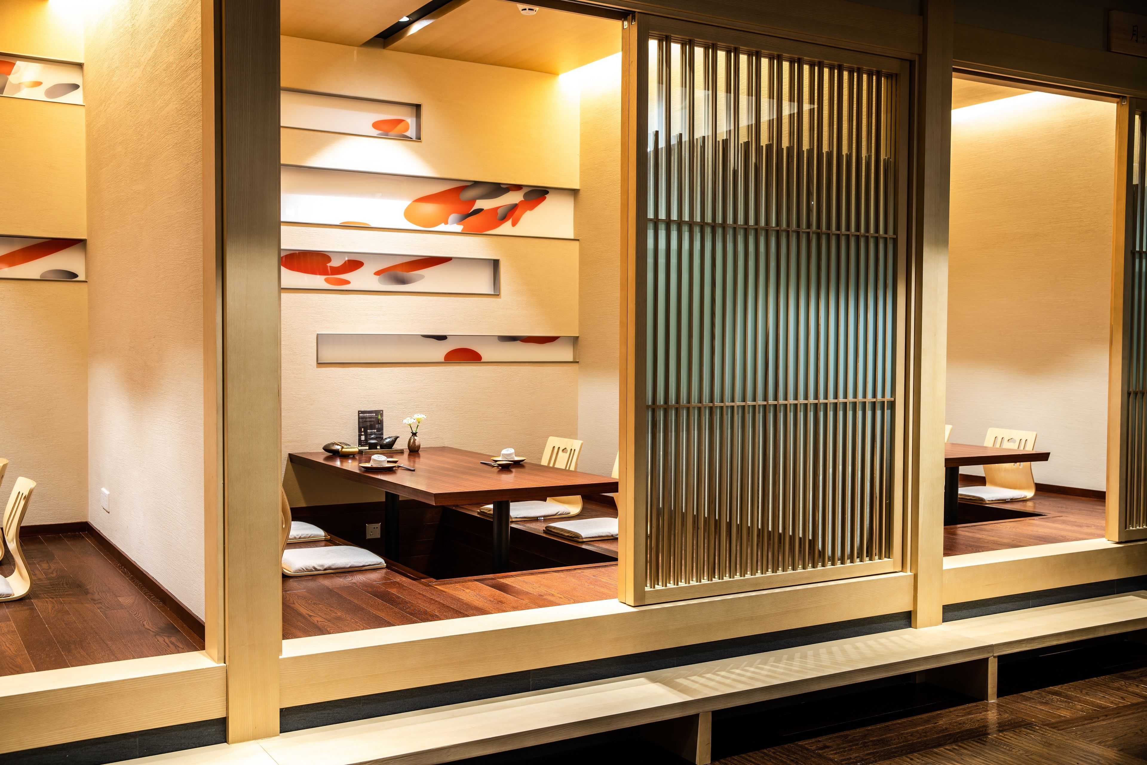 Una sala de conferencias moderna con una mesa de madera, sillas y una pared decorativa con patrones abstractos.