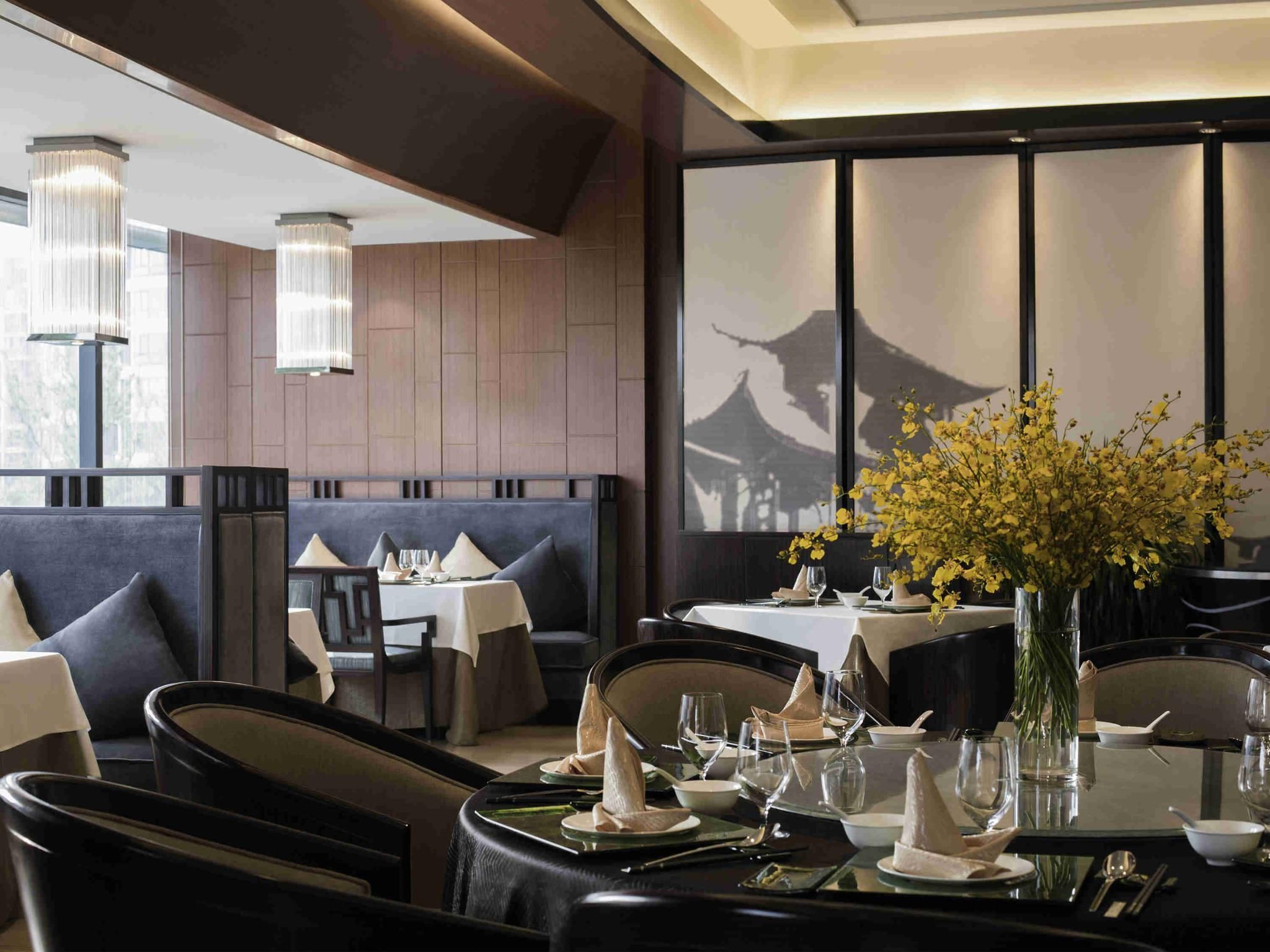 A restaurant with dark wood paneling, modern lighting, and a traditional Asian architectural view.