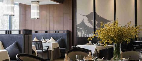 A restaurant with dark wood paneling, modern lighting, and a traditional Asian architectural view.