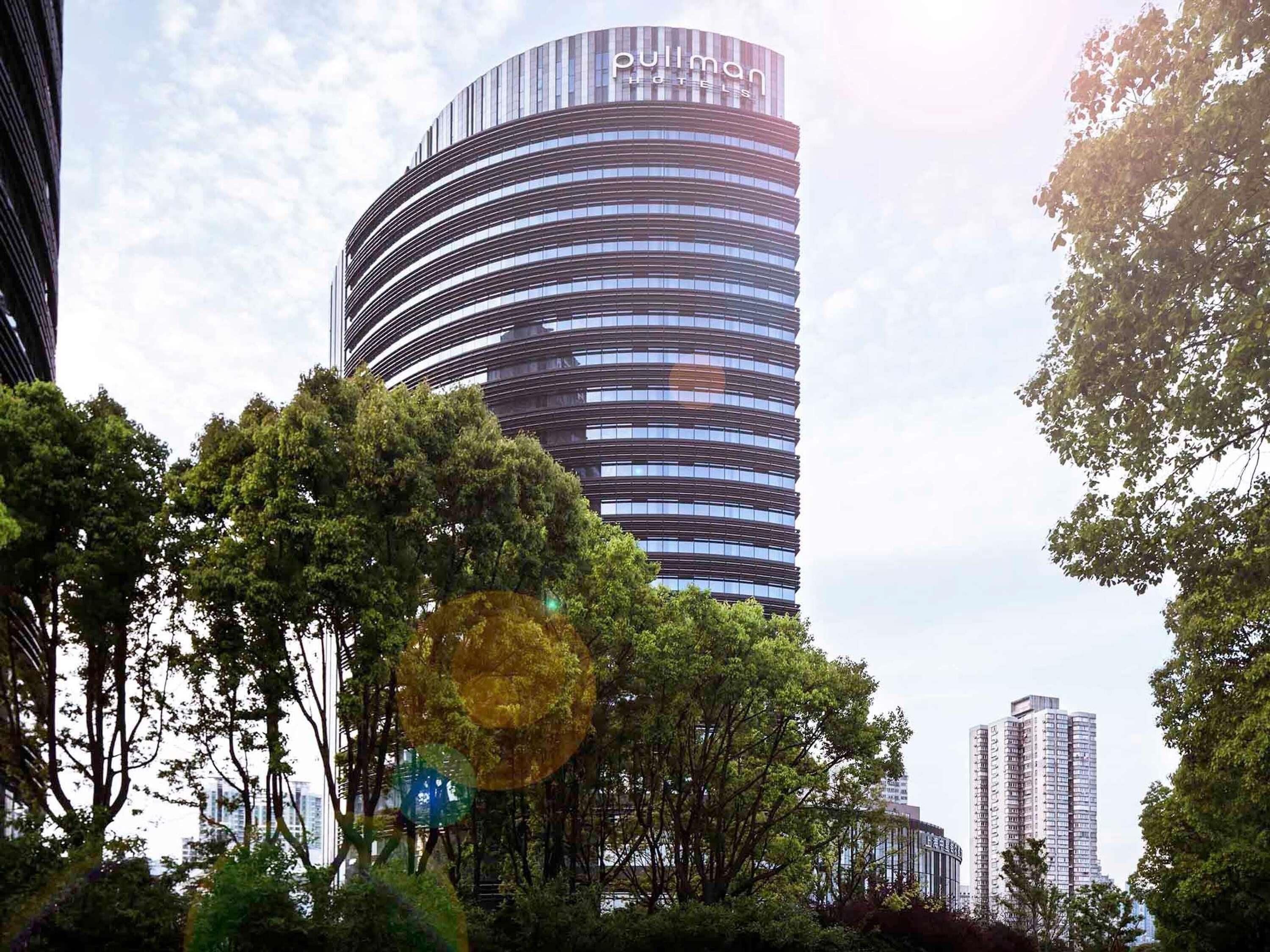 Un hotel moderno con una fachada curva y un llamativo letrero de 'Pullman Hotels'.