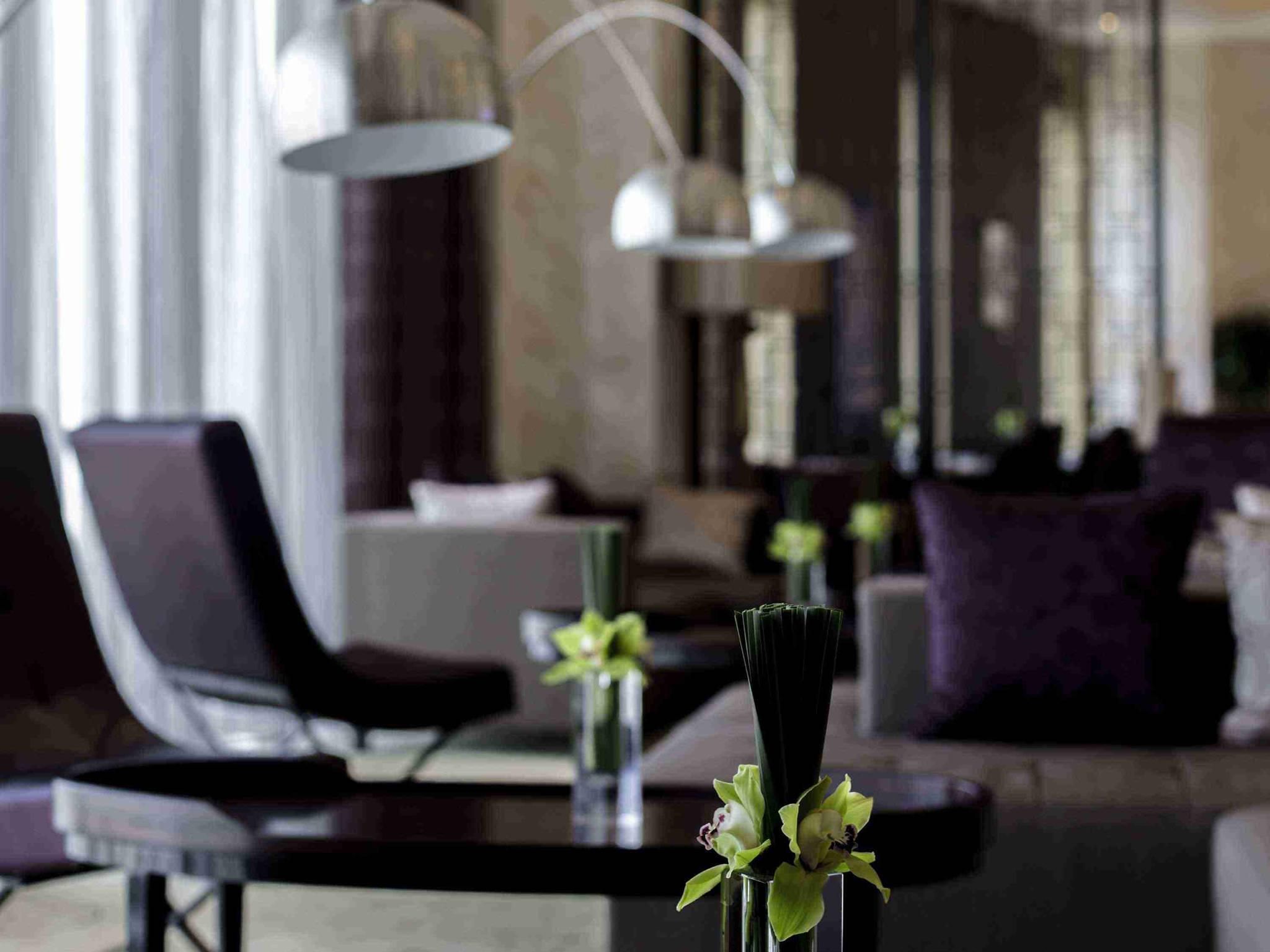 A modern interior with a dark-toned sofa, a glass coffee table, and a vase with flowers.