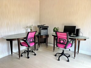 Ein moderner Büroarbeitsplatz mit zwei Schreibtischen, jeweils mit Stuhl, Drucker und Computermonitor.