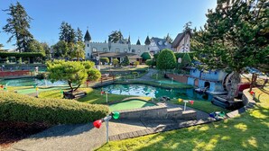 Ein Minigolfplatz mit einem schlossartigen Gebäude im Hintergrund.