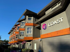 A multi-story building with a grey facade, wooden accents, and a visible sign reading "COAST".