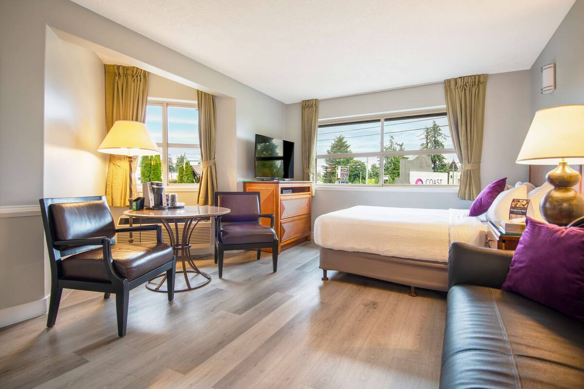 Une chambre d’hôtel équipée d’un lit, d’un bureau, d’une chaise, d’une table et d’un téléviseur.