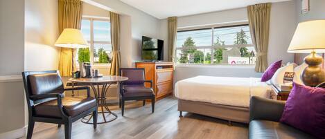 Una habitación de hotel con cama, escritorio, silla, mesa y televisor.