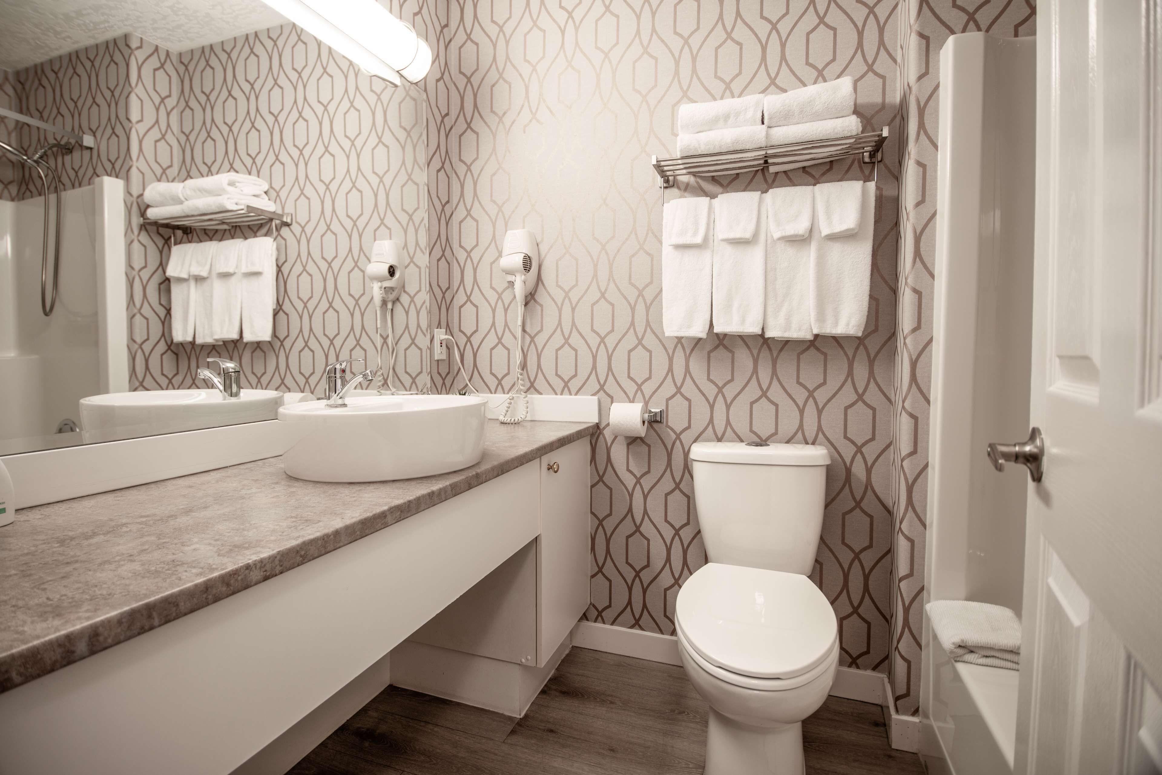 Un baño con pared estampada, lavamanos, inodoro y toallero.