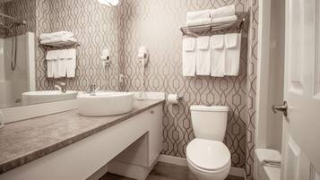 Un baño con pared estampada, lavamanos, inodoro y toallero.