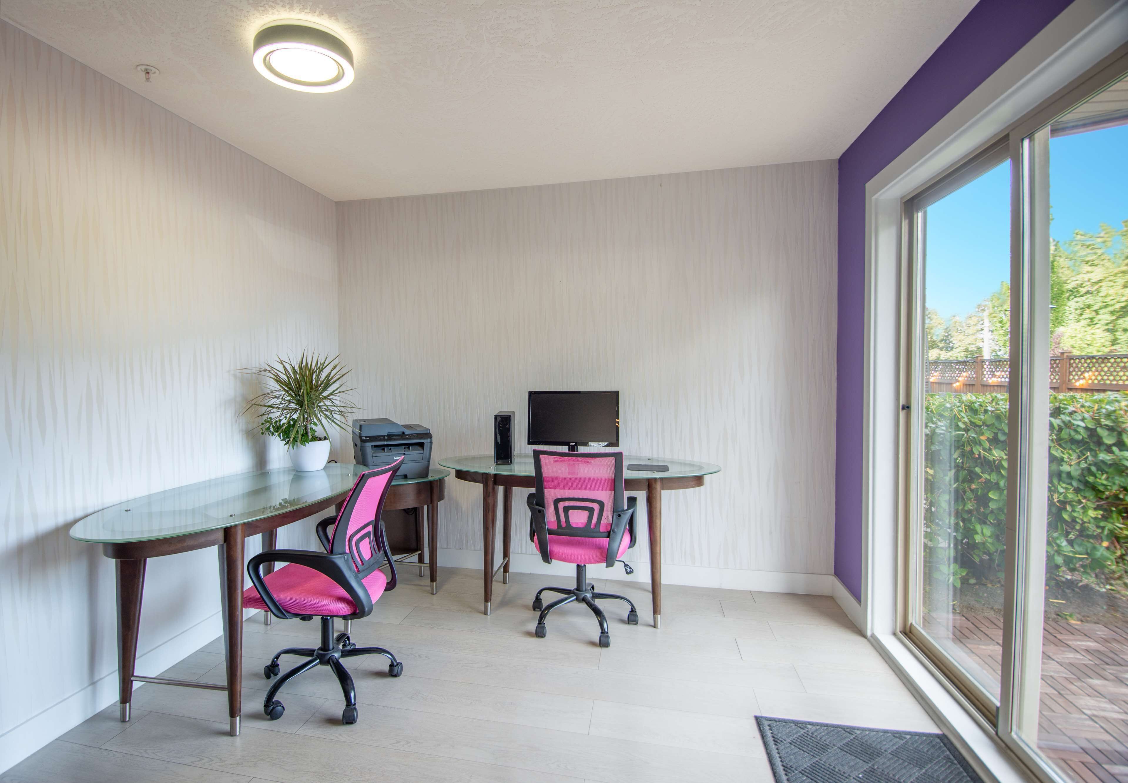 Un petit bureau avec deux bureaux, deux chaises, une plante en pot et un téléviseur.