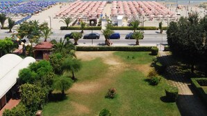 Ein Strandresort mit Reihen von Sonnenschirmen und Liegestühlen, einem Parkplatz und Blick auf das Meer.