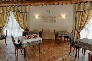 A dining area with two tables, chairs, and a decorative wall piece. - Hotel Villa Luigi (Martinsicuro)