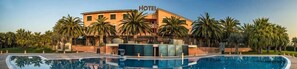 A hotel with a pool, palm trees, and a clear sky. - Hotel Villa Luigi (Martinsicuro)