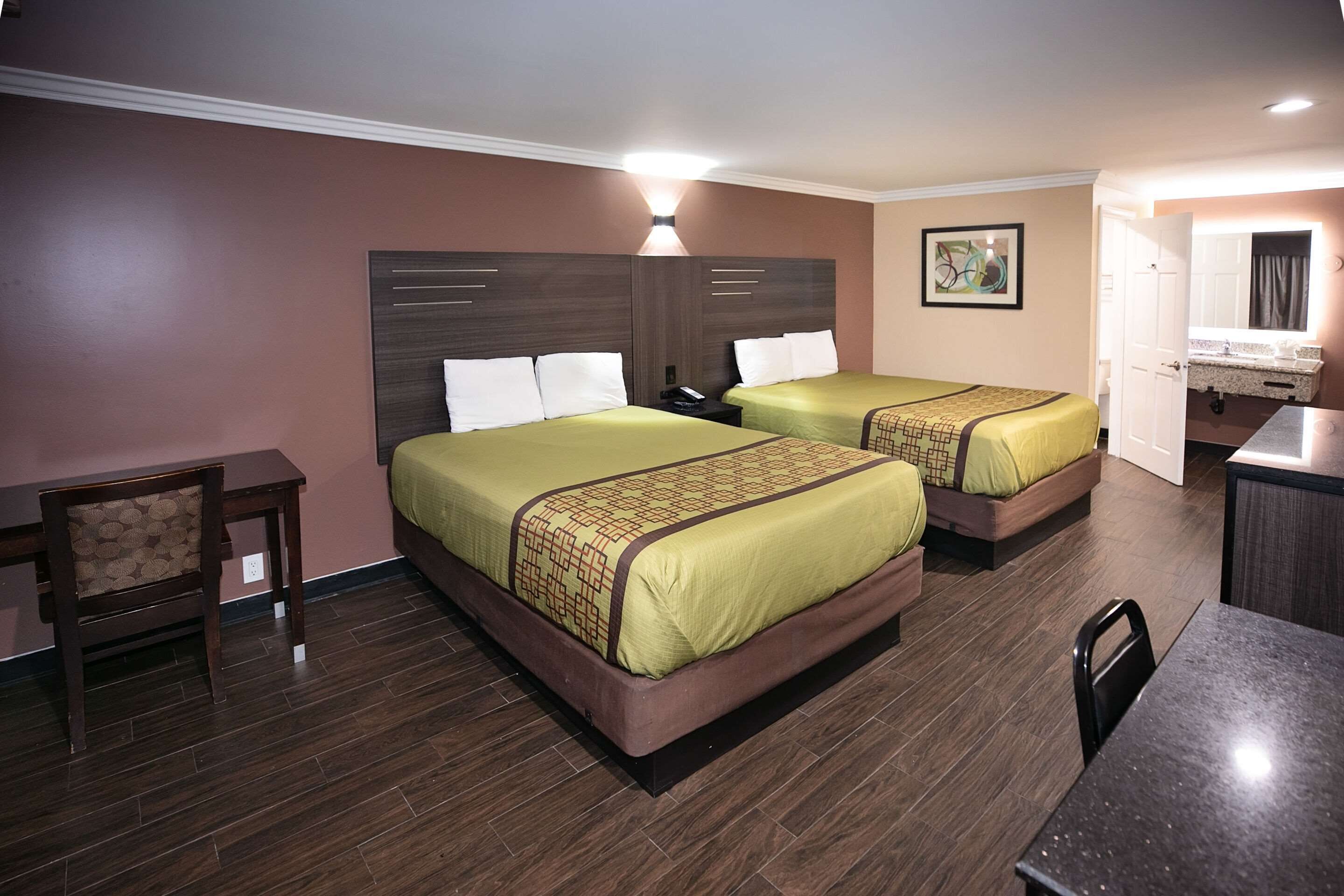 A hotel room with two beds, a desk, and a chair.