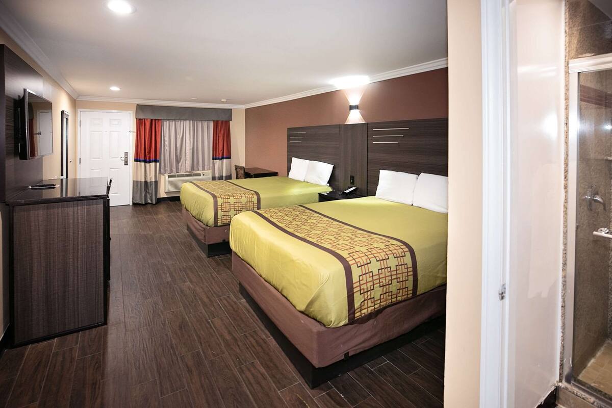 Una habitación de hotel con dos camas, un escritorio y una televisión.