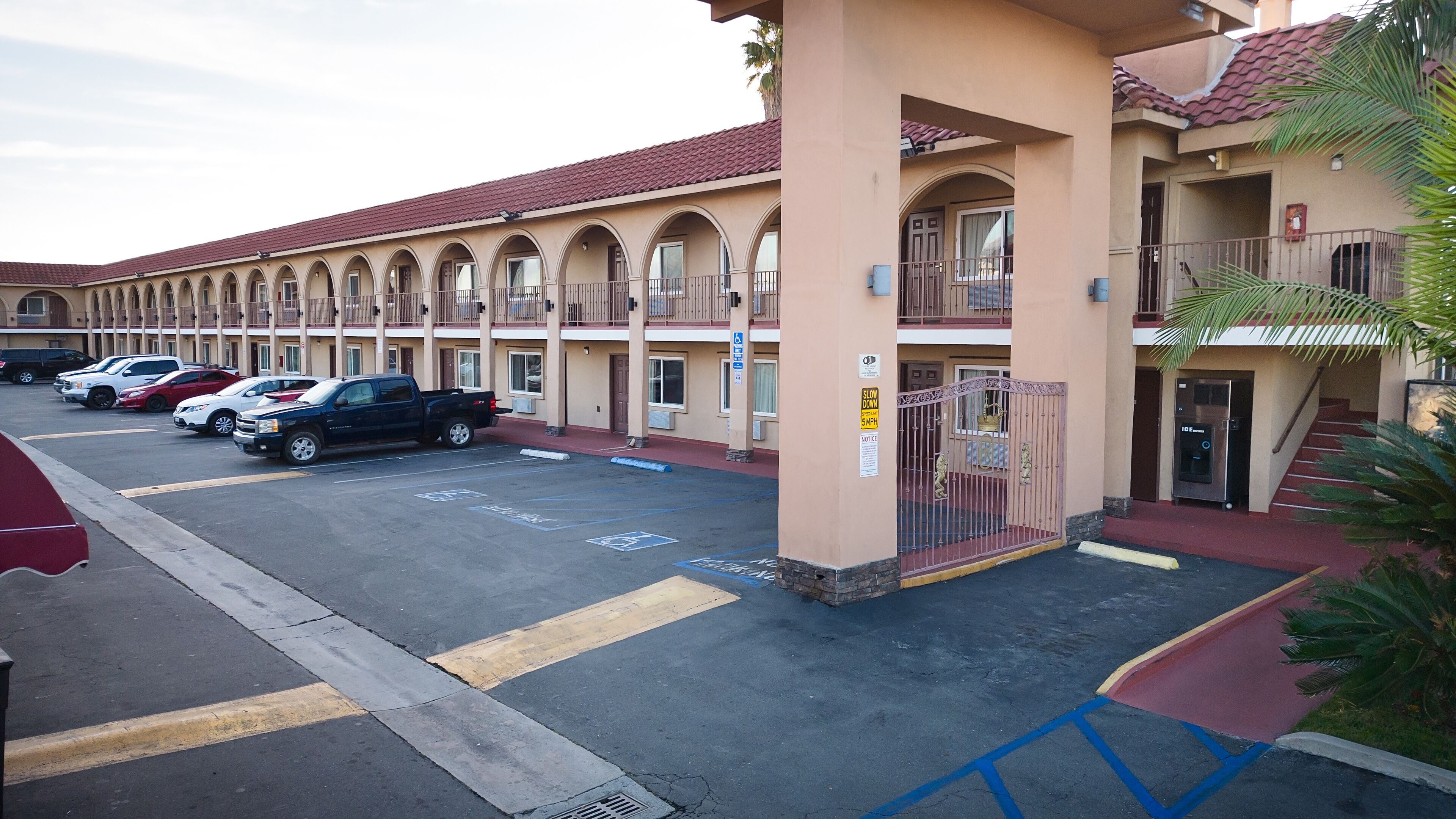 A motel with multiple balconies, a parking lot, and a gated entrance.