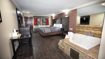 Hotelkamer met een bed, bureau, televisie, grote spiegel, badkuip en raam met gordijnen.