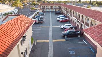 A motel with a red-tiled roof, a parking lot with several cars, and a central walkway.