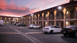 A motel with a row of rooms, each with a balcony and a small porch. There are several cars parked in the lot. - Rodeway Inn & Suites Bellflower (Bellflower)