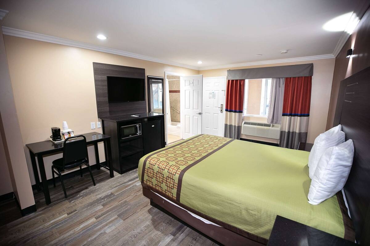 Una habitación de hotel con cama, escritorio y televisión.