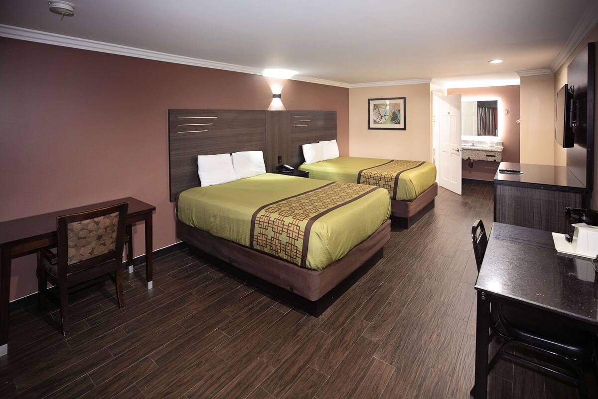 Una habitación de hotel con dos camas, un escritorio, una silla y un televisor.