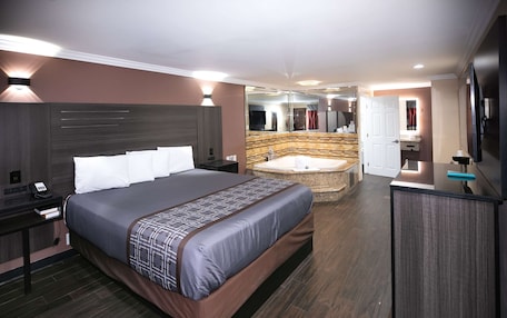 A modern hotel room with a large bed, a separate bathroom with a bathtub, and a flat-screen TV.