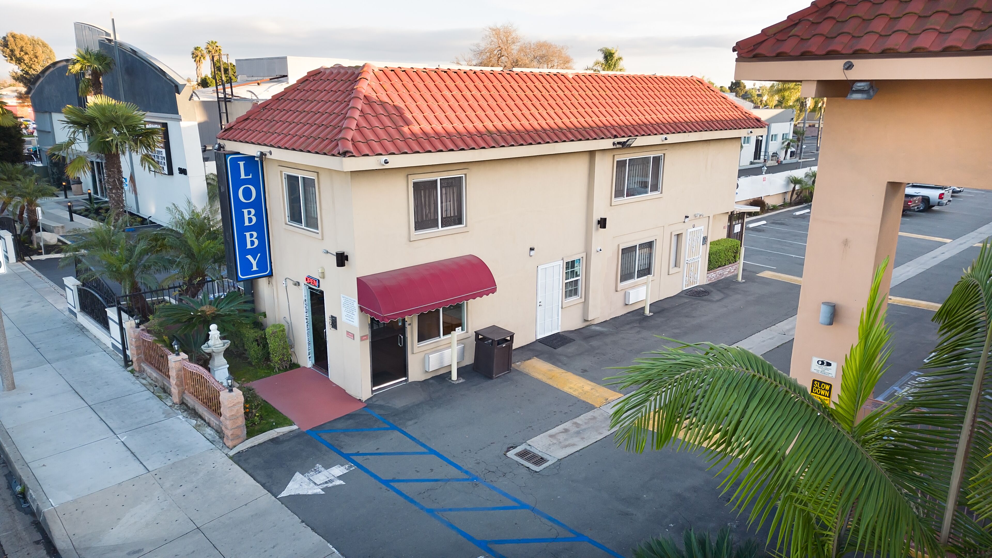 A hotel with a red-tiled roof, a red awning, and a sign that reads "LOBBY".