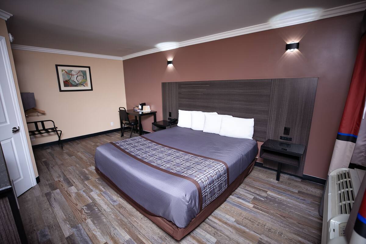 Una habitación de hotel con una cama grande, un escritorio, una silla, una mesita y un calentador fijado a la pared.