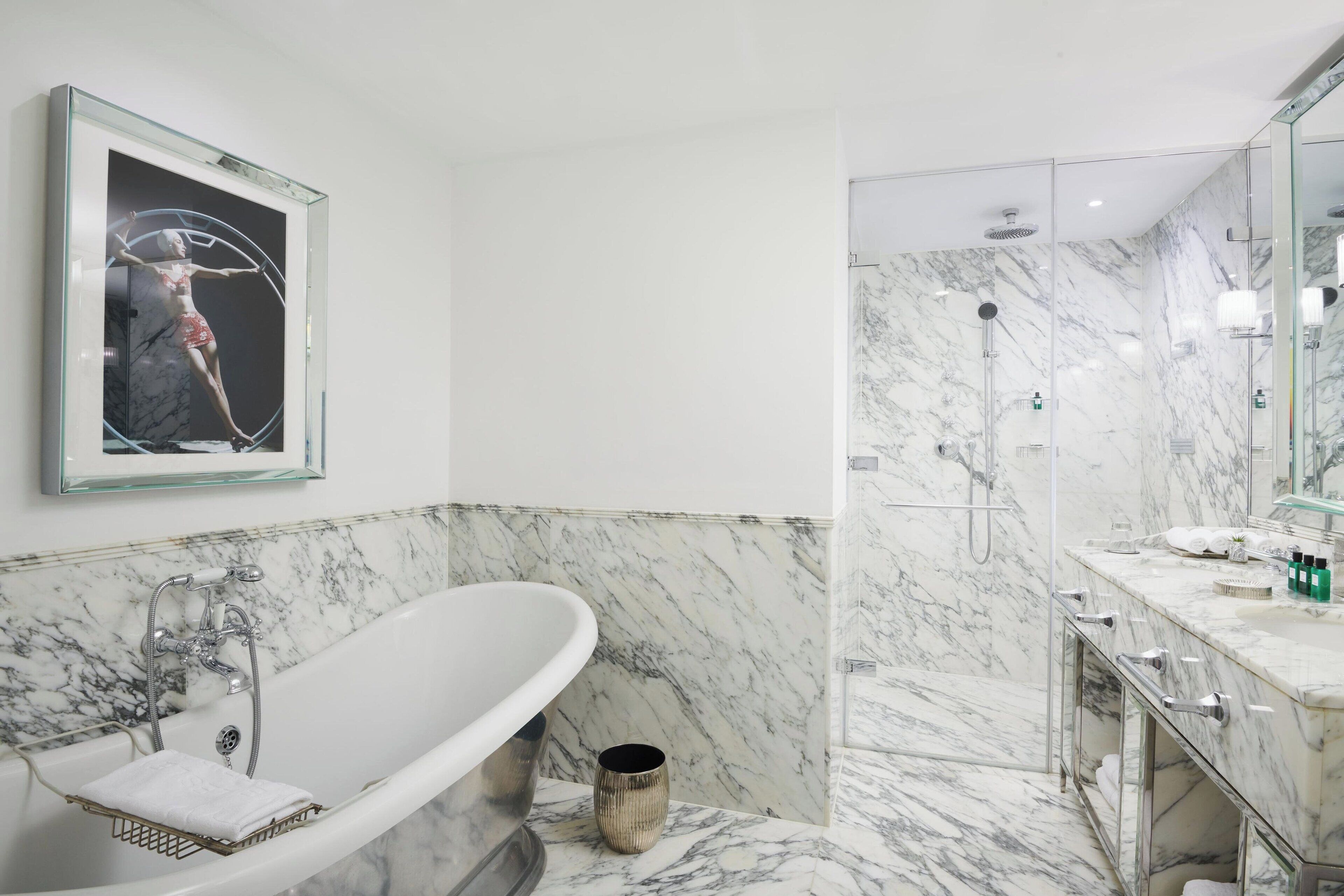Un bagno moderno con una vasca freestanding, un angolo doccia e un rivestimento in marmo.