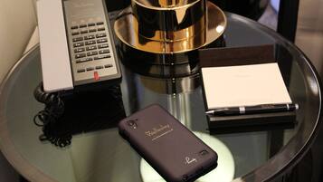 Une table en verre avec un téléphone noir, un stylo, un carnet et un téléphone.