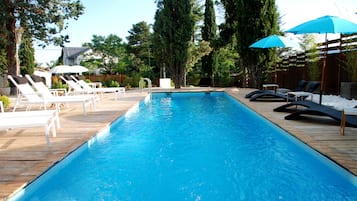 Una piscina al aire libre, sillones reclinables de piscina