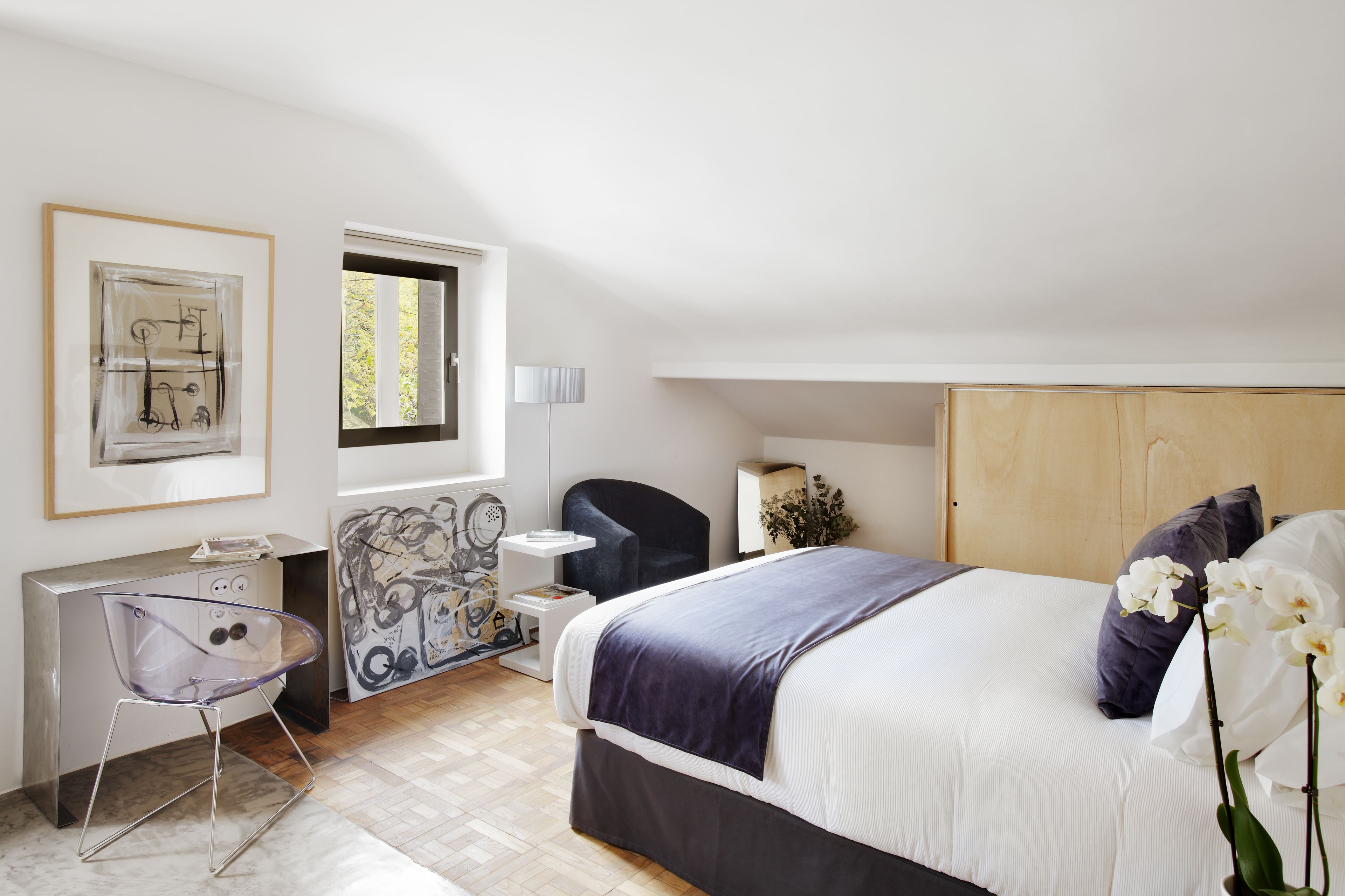 A modern bedroom with a bed, a desk, and a chair.