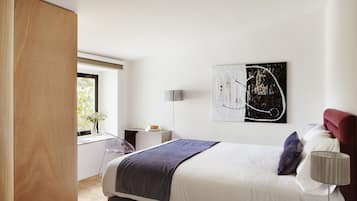 Un dormitorio moderno con una cama grande, una mesita de noche, una lámpara y una ventana con vistas.