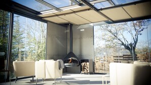 Un espace extérieur moderne, aménagé avec des sièges, une paroi de verre, une cheminée et une pile de bois de chauffage.