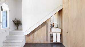 Un escalier menant à une salle de bain équipée d’un lavabo et d’un miroir.