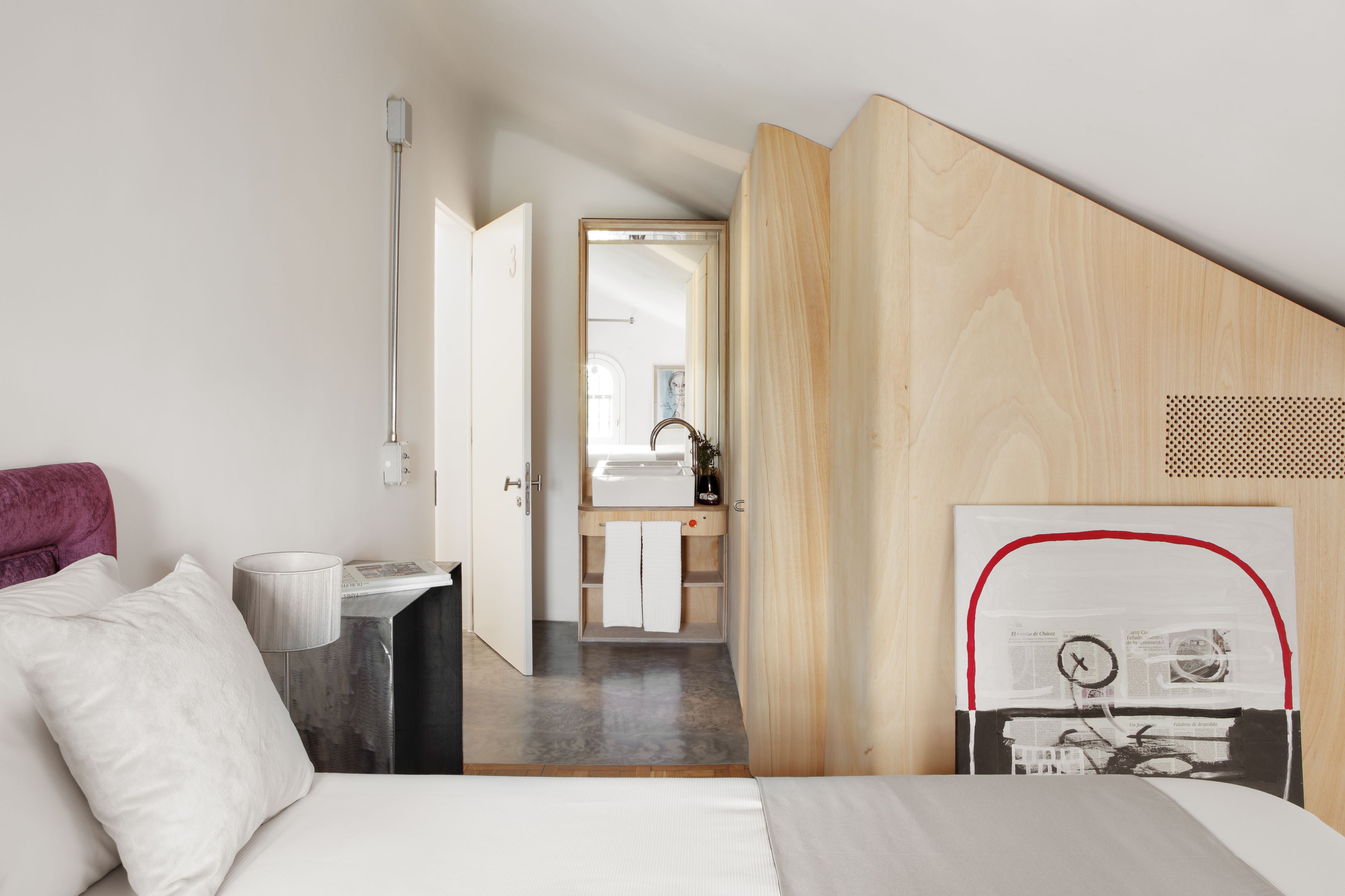 Una camera d'albergo moderna con un letto, una scrivania, uno specchio e vista sul bagno.