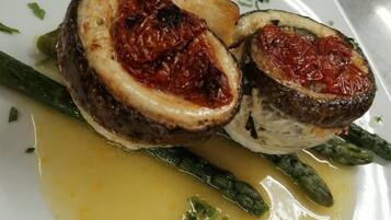 Un plato con un rollito de carne relleno, espárragos y salsa amarilla.