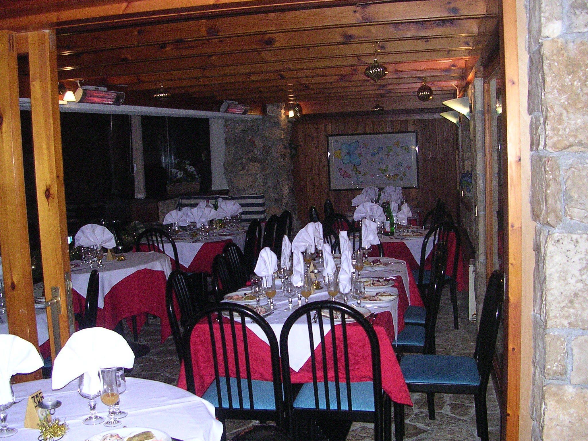 Una sala ristorante con diversi tavoli apparecchiati, soffitto in legno, pareti in pietra e una mappa appesa al muro.
