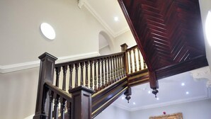 A grand staircase with a wooden handrail and striped carpeted steps. - Palmerston Suites (Edinburgh)