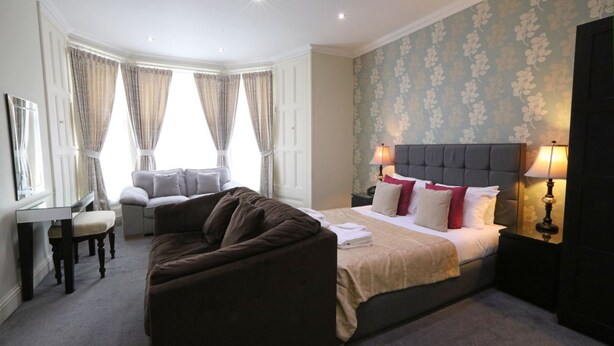 A hotel room with a bed, a sofa, a desk, and a chair. - Palmerston Suites (Edinburgh)