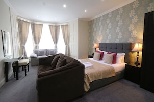 A hotel room with a bed, a sofa, a desk, and a chair.