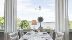 A dining table set for two with a view of a lake and a flag. - Sigtuna Stadshotell (Sigtuna)
