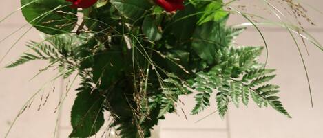 A clear glass vase with red roses and green foliage.