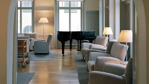 A living room with a grand piano, sofas, and lamps. - Sigtuna Stadshotell (Sigtuna)
