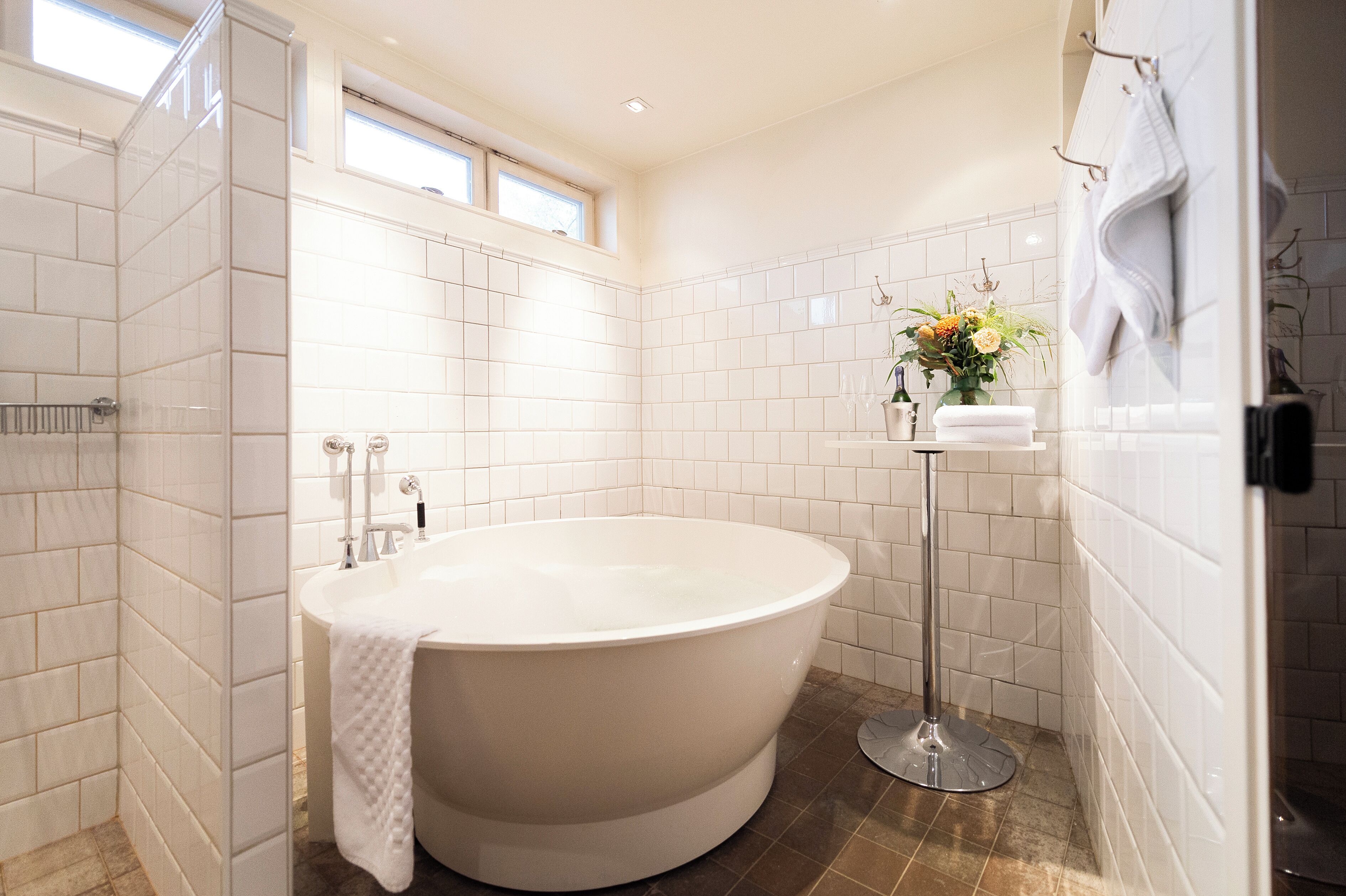 Une salle de bain moderne avec une baignoire sur pieds, une douche à parois de verre et une petite fenêtre qui laisse entrer la lumière naturelle.