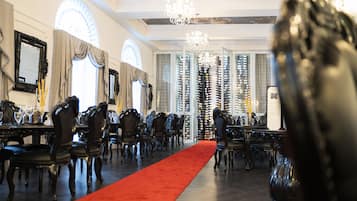A formal dining room with a red carpet, ornate chairs, and a chandelier.
