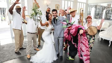 A group of people in a room with a large window, a white sofa, and a chandelier.
