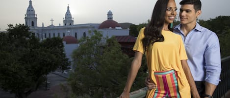 Um casal parado em uma ponte com vista para uma grande igreja com cúpulas e torres.