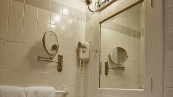 A bathroom with a sink, mirror, towel rack, and wall-mounted hairdryer.