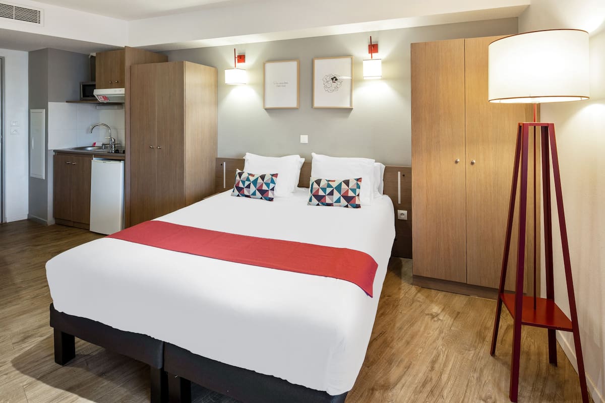 A hotel room with a large bed, a desk, and a wardrobe.
